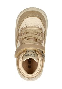 Tan en beige sneaker met een bovenwerk van suede en glad leer, gewatteerde kraag, ronde neus, perforaties en klittenbandsluiting.
