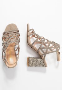 Sandali in suede beige con cinturini, caratterizzati da un design geometrico, dotati di dettagli in strass e un tacco quadrato intrecciato testurizzato.