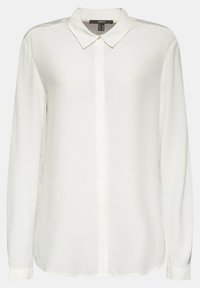 Blouse blanche à manches longues pour femme avec col pointu et boutons devant cachés, présentée sur un fond uni.