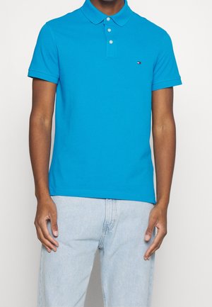 Koszulka polo z krótkim rękawem w jasnoniebieskim kolorze, wykonana z bawełny, z kołnierzykiem i zapięciem na trzy guziki. Mały logotyp na klatce piersiowej.