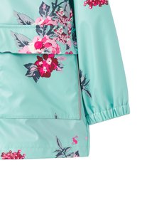 Lys blå vandtæt jakke med pink og lilla blomsterdesign, elastiske manchetter og en frontlomme med en pink knap.