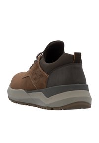 Chaussure en faux cuir marron avec un design texturé, un col rembourré et une semelle en caoutchouc grise avec un motif de semelle pour l'adhérence.