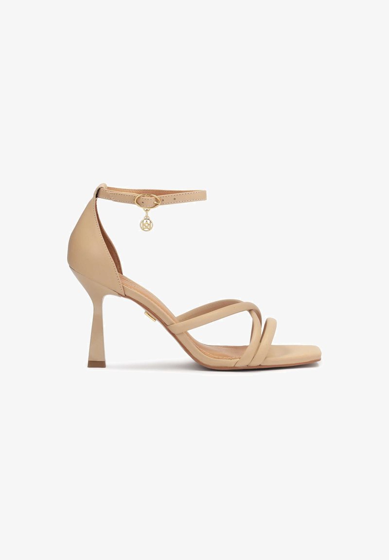 Nude nahkahigh heel sandaalit, joissa on nilkkahihna, risteilevät hihnat varpaissa, pyöreä varpaiskäyttölaatikko ja kultainen metalliyksityiskohta.