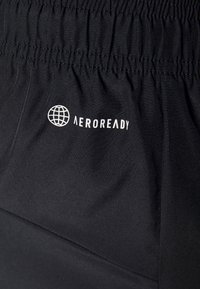 Tissu noir avec taille élastique froncée présentant une icône de globe blanche et le mot "AEROREADY" imprimé en dessous.
