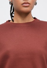 Bordeauxrød bomulds-sweatshirt med rund halsudskæring, blød tekstur og løs pasform. Har et diskret meleret mønster og ribstrikkede manchetter.