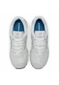 White New Balance 574 sneakers with mesh and suede upper, blue insoles, flat white laces, and distinctive reflective logo accents.