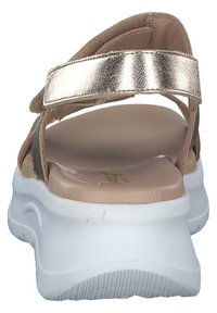 Damsandaler med ett metallic guldrem, beige fotbädd och en tjock vit sula med texturerat mönster för bra grepp.