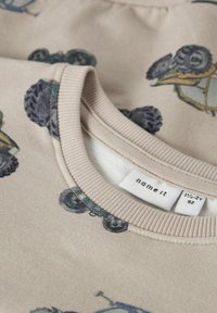 Bežna trenirka z barvitimi tiskanji traktorjev in gum. Pleteni okrogli izrez in mehak material. Vidna blagovna znamka znotraj.