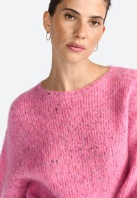 Maglione rosa lavorato a maglia con una vestibilità ampia, scollo rotondo e tessuto testurizzato. Presenta delicati spruzzi di colore sparsi.