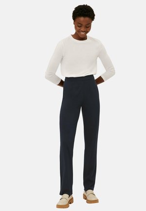Navy high-waisted trousers with a straight leg design, paired with a fitted white long-sleeve top. Smooth fabric with minimalist style details.