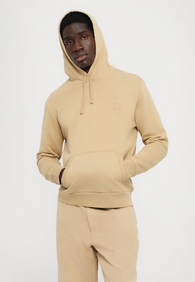 Beige hoodie i mjukt material, med en känguruficka och ett präglat logotyp. Huvtröja med dragsko och ribbade muddarn för en bra passform.