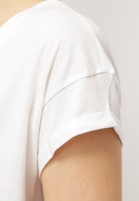 Hvid bomulds T-shirt med opskruede korte ærmer og en blød tekstur, der har en klassisk rund halsudskæring og en afslappet pasform.
