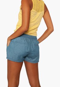 Denimshortsit, jossa on elastinen vyötärönauha, vaaleansininen väri, kaksi takataskua ja rento malli, yhdistettynä keltaiseen hihattomaan puseroon.