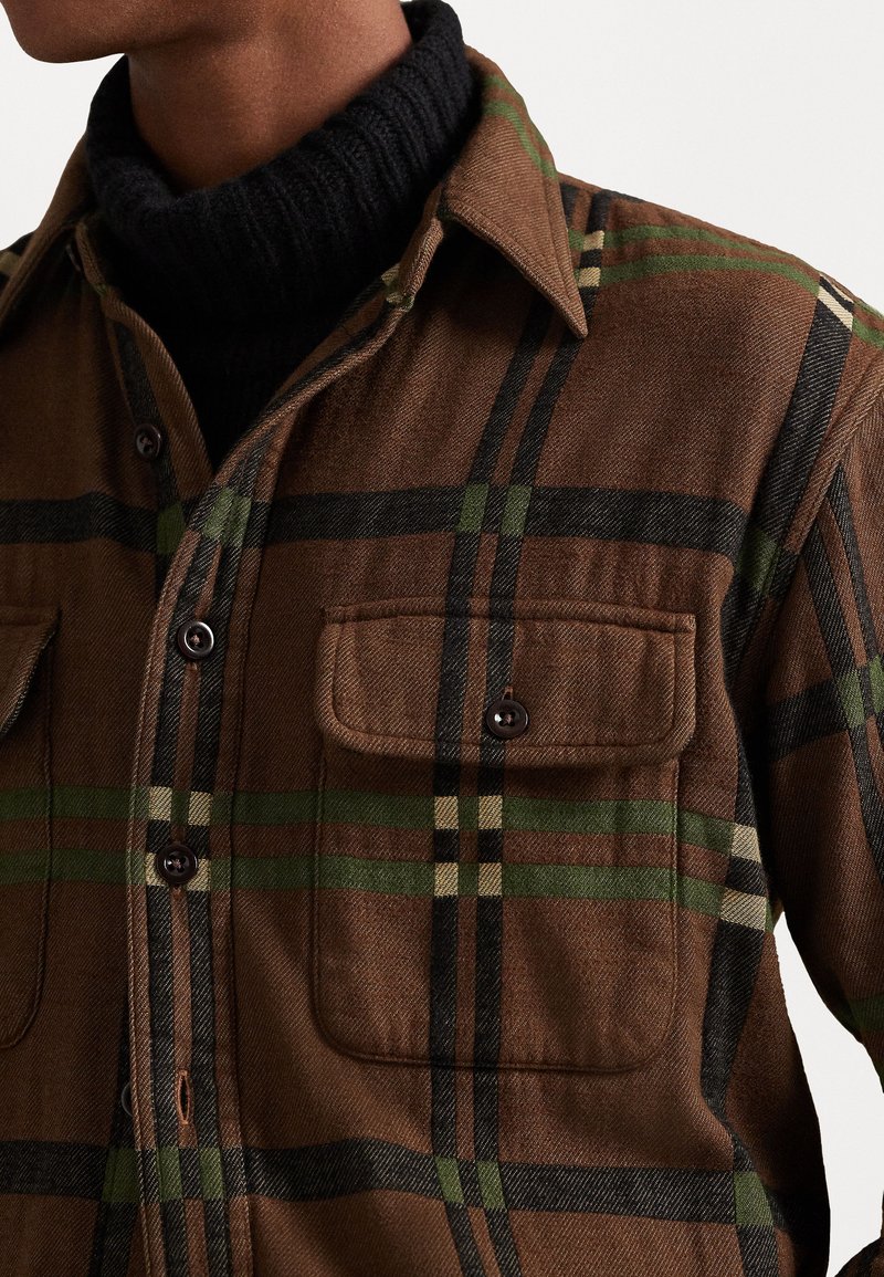Camicia a scacchi marrone realizzata in tessuto; presenta linee verdi e nere, chiusura con bottoni, due tasche sul petto e colletto classico.