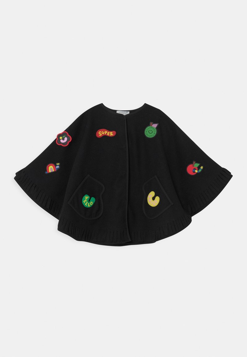 Cape noire avec poches avant, décorée de patchs colorés et ludiques incluant des fleurs, des fruits, un arc-en-ciel et le texte "SUPER".