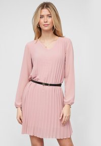 Abito rosa plissettato con maniche lunghe e scollatura a V. Presenta una cintura nera in vita e una gonna fluente. Tessuto morbido e leggero.
