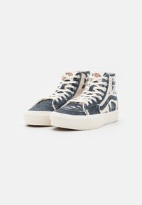 Höga sneakers i blått och cremefärgat mönstrat canvas med vita skosnören, texturerade detaljer och en beige gummisula.