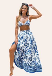 Bikini set met een blauw bloemenpatroon op een witte achtergrond, gecombineerd met een bijpassende lange rok met een gerimpelde zoom en blauwe accenten.