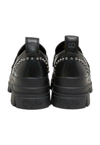 Svarta plattformssneakers med nitar på hälen, med en texturerad sula och dubbla dragflikar för enkel påtagning. Logotyp tryckt på remmarna.