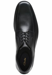 Scarpa da uomo in pelle nera con un design elegante, punta rotonda, lacci e cuciture ridotte al minimo. L'etichetta interna riporta la scritta "Clarks".
