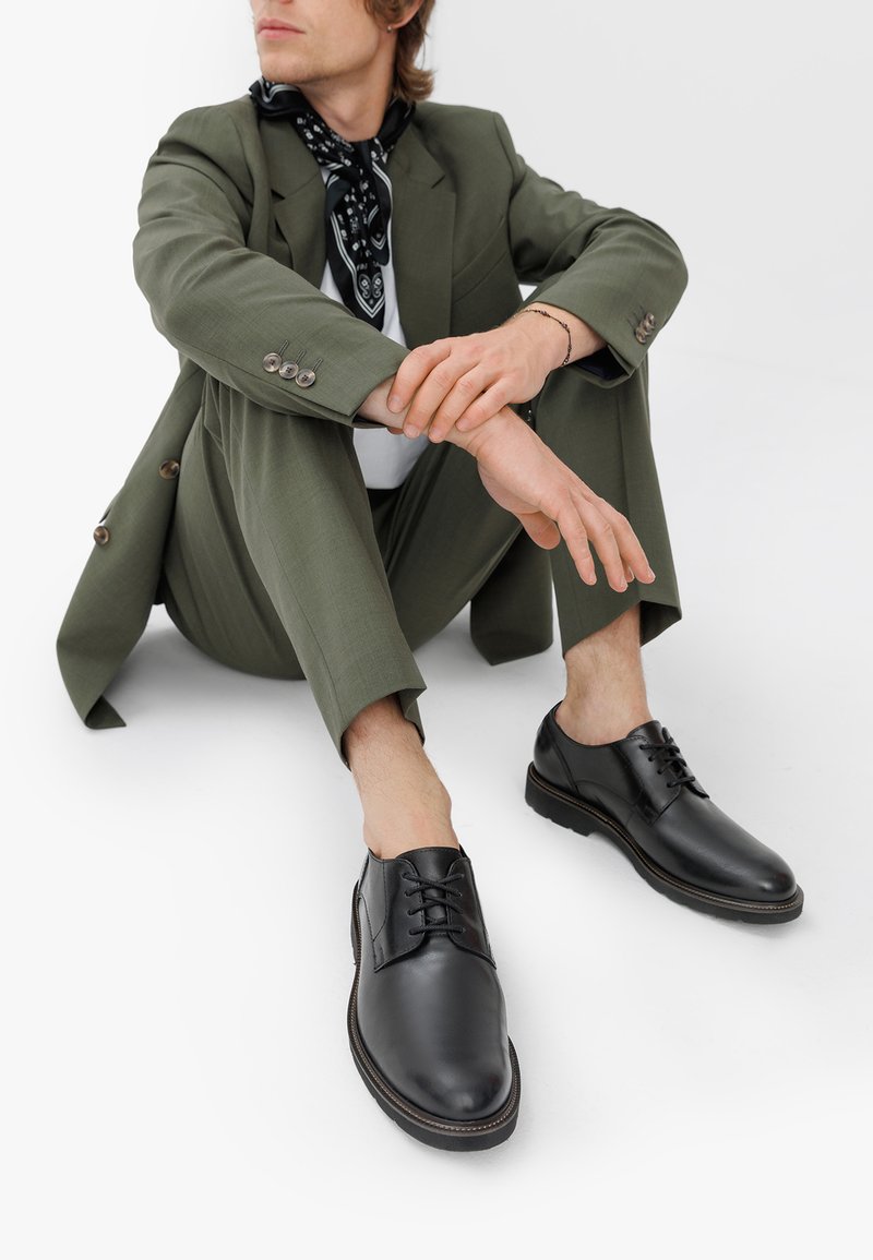 Scarpe eleganti in pelle nera con finitura liscia, punta rotonda e design con lacci. Presentano cuciture sottili e una suola resistente.
