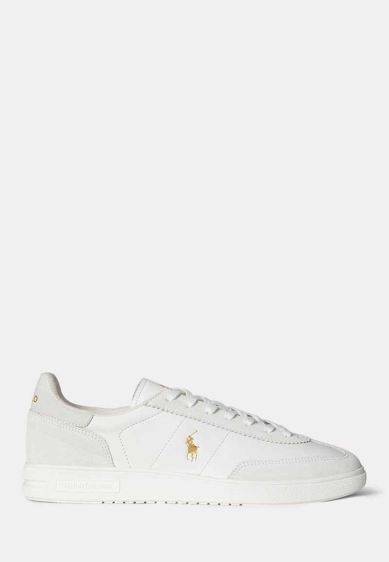Baskets basses blanches avec design à lacets, logo Polo Ralph Lauren doré sur le côté et semelle texturée sur fond uni.