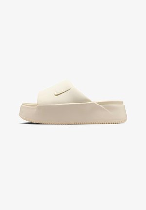Beige Nike slip-in sandal med tyk sål og et guld Nike swoosh-logo på den brede rem mod en hvid baggrund.