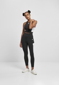 Mustat ja valkoiset urheilulliset crop-top ja korkeavyötäröiset leggingsit, joissa on tyylikäs muotoilu, joustava kangas ja kontrastiväriset sivupaneelit.