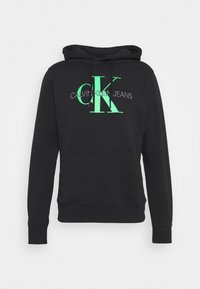 Felpa nera in cotone con tasca a marsupio frontale, cappuccio con cordoncino e grande logo stampato verde con la scritta "CALVIN KLEIN JEANS."