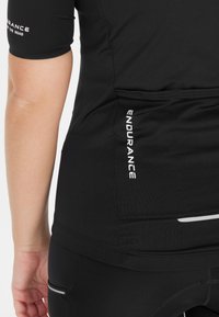 Schwarzes Sportshirt mit kurzen Ärmeln, mit weißem "ENDURANCE"-Text. Glatte Textur, taillierte Passform und reflektierende Akzente am Saum.