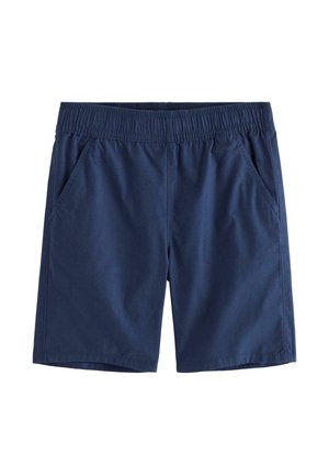 Ung dreng iført en blå t-shirt med hajprint, blå shorts, matchende bøllehat med hajprint og marineblå høje sneakers, går fremad.