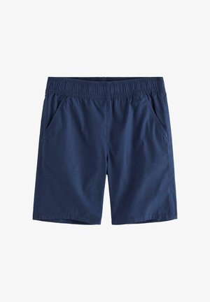 Ung dreng iført en blå t-shirt med hajprint, blå shorts, matchende bøllehat med hajprint og marineblå høje sneakers, går fremad.