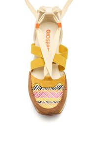 Chaussure en tissu jaune avec des straps croisés, présentant une boîte à orteils en daim brun texturé et un motif tissé coloré avec des accents roses, noirs et jaunes.