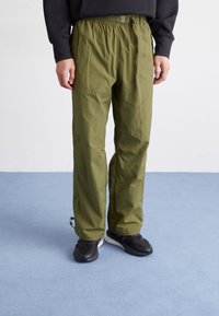 Pantalones verdes, ligeros, con cintura elástica y cinturón. Presentan puños en los tobillos ajustados y un acabado suave y texturizado.