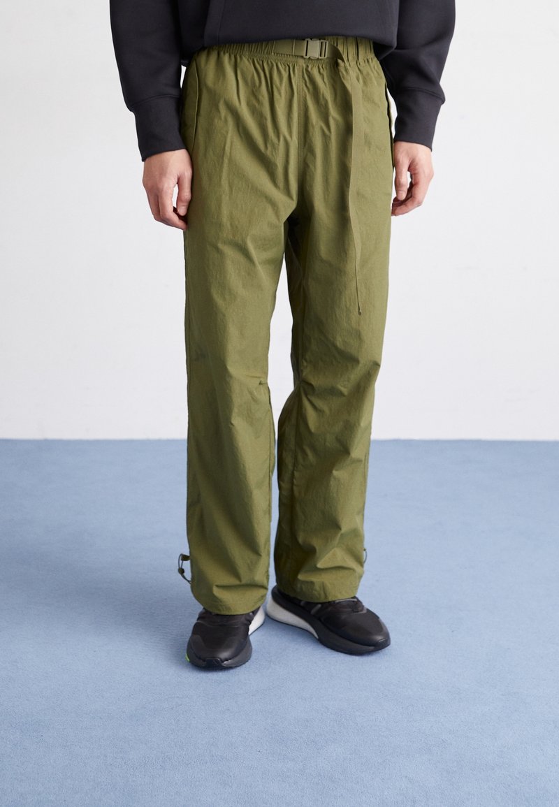 Pantalones verdes, ligeros, con cintura elástica y cinturón. Presentan puños en los tobillos ajustados y un acabado suave y texturizado.