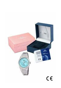 Reloj de acero inoxidable plateado con una esfera azul clara, función de fecha y brazalete de malla, junto a una caja de regalo rosa y una tarjeta de garantía.