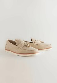Beige Wildleder Loafers mit gewebten Textilakzenten, Quasten-Detail und kontrastierender brauner Außensohle, ausgestattet mit einer weißen Zwischensohle für zusätzliche Stabilität.