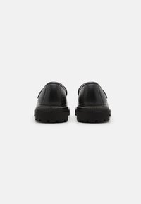 Des chaussures en cuir noir avec une finition texturée, dotées d'une semelle en caoutchouc noir robuste et de coutures renforcées pour plus de durabilité.