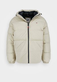 Chaqueta acolchada beige con cremallera frontal, puños elásticos, capucha y pequeño logo de Tommy Jeans en el pecho y en el interior del cuello.