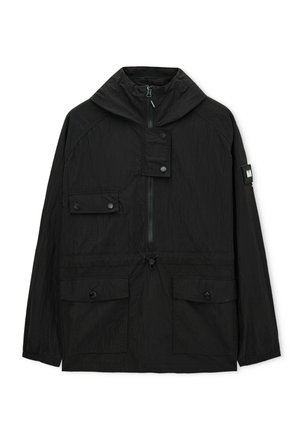 Giacca nera con cappuccio, cerniera frontale, tre tasche con patta e bottone, vita regolabile con coulisse e dettaglio a toppa sulla manica sinistra.