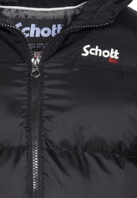 Sort pufferjakke lavet af glat stof med synlige syninger og en frontlynlås. Har "Schott" logo i hvid og rød broderi på brystet.