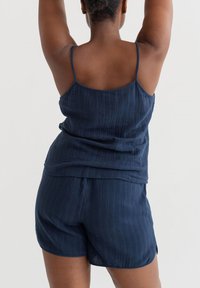 Nachtwäsche-Set in Navyblau mit einem ärmellosen Top mit dünnen Trägern und passenden Shorts. Der Stoff hat eine subtile, strukturierte Oberfläche.