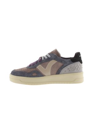 Sneaker low-top con pannelli in suede grigio, viola e beige, suola crema e borchie metalliche nella zona del tallone.