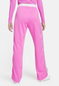 Rozā sporta bikses ar plaša kāju dizainu, elastīgu jostasvītru un kontrastējošām baltām sānu svītrām. Izgatavotas no gludas, vieglas auduma.