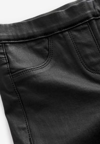 Los pantalones de mezclilla negros presentan una textura suave, un diseño tradicional de cinco bolsillos y costuras en contraste a lo largo de las costuras.
