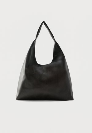 Sac bandoulière en cuir noir lisse avec une large sangle unique et un design décontracté et minimaliste sur un fond uni.