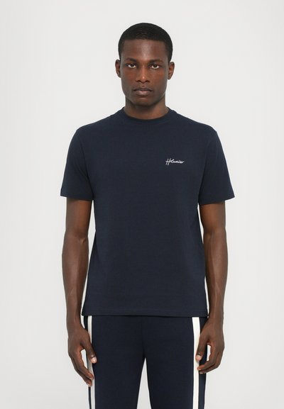 T-shirt bleu marine à manches courtes en tissu doux, avec un col rond et un petit logo brodé sur la poitrine.