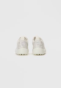 Un paio di sneaker bianco sporco con un sottile motivo topografico, suole spesse e linguette posteriori, viste da dietro su uno sfondo semplice.