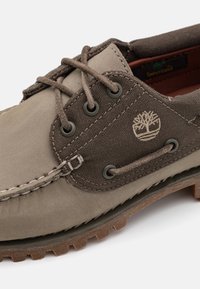 Braune Canvas- und Lederschuhe mit runden Schnürsenkeln, Metallösen und Gummisohle. Verfügt über ein gesticktes Design und eine geprägte Logodetail.