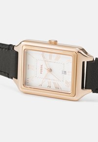 Rechteckige Fossil-Armbanduhr mit einem Gehäuse aus Roségold, weißem Zifferblatt, schwarzem Lederarmband und römischen Ziffern. Mit Datumsanzeige bei 6 Uhr.
